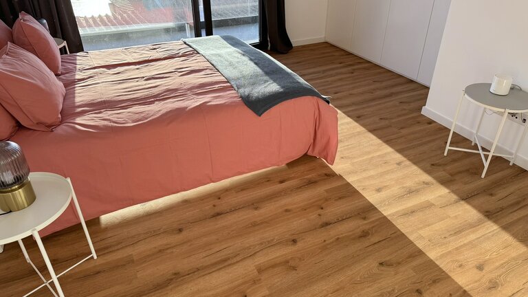 Modernes Schlafzimmer mit Holzoptik-Vinylboden, rosa Bett und weißen Möbeln